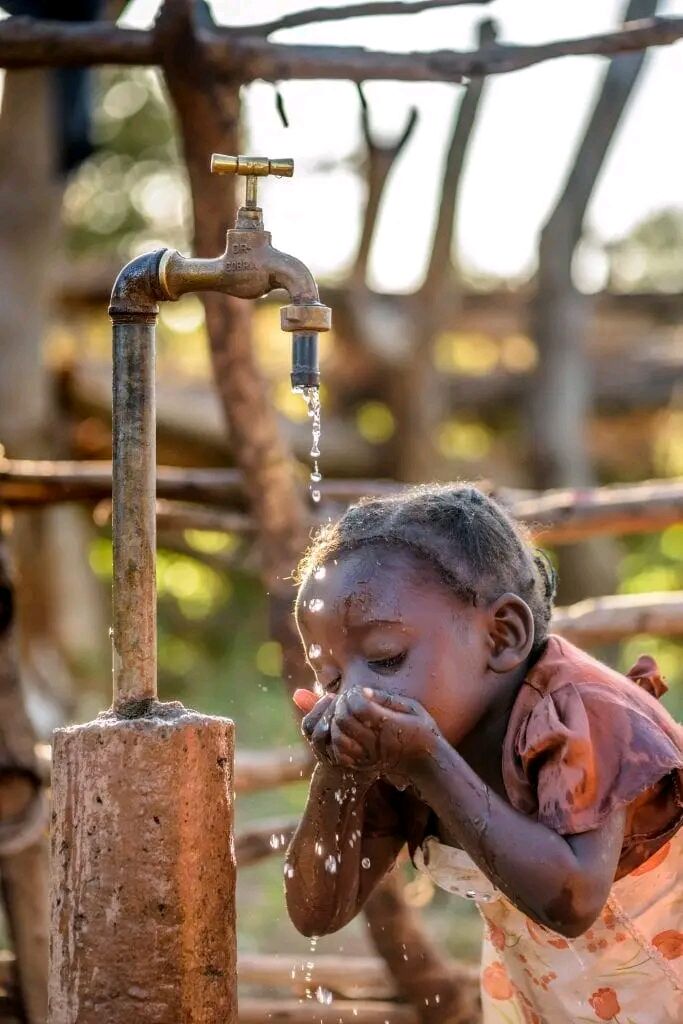Un enfant boit à une borne-fontaine du quartier, SALICON RDC.